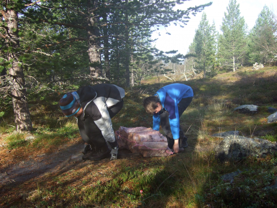 To barn som jobber sammen og løfter en sekk med ved