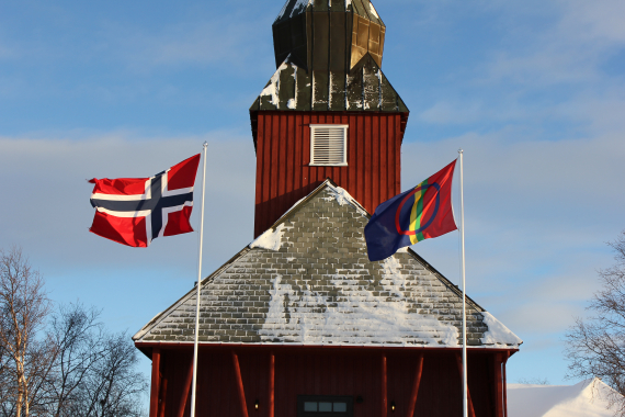 Det samiske flagget og det norske flagget foran Kautokeino kirke.